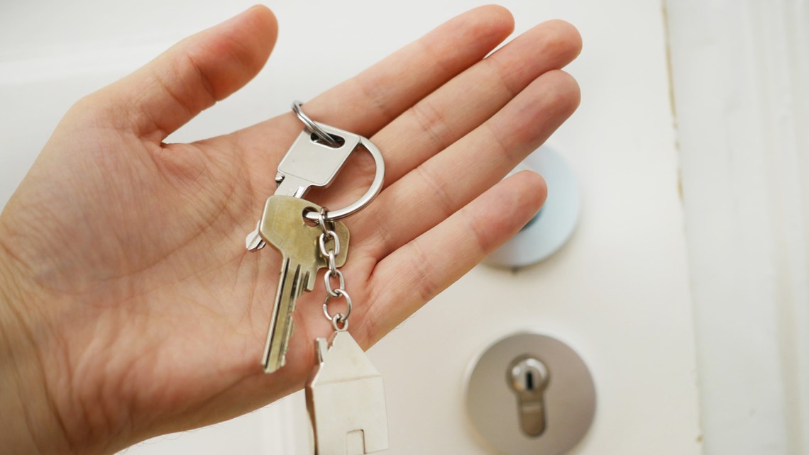 Hand holding house keys with front door in the background | BetterBond